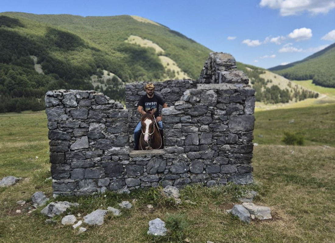 Uomo a cavallo dentro un vecchio rudere in pietra a Piano Ruggio &copy;Riccardo Sartori