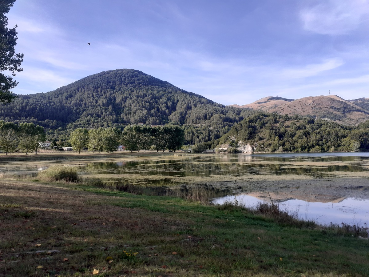 Specchio d'acqua del Lago di Mormanno circondato da alberi e rilievi montuosi