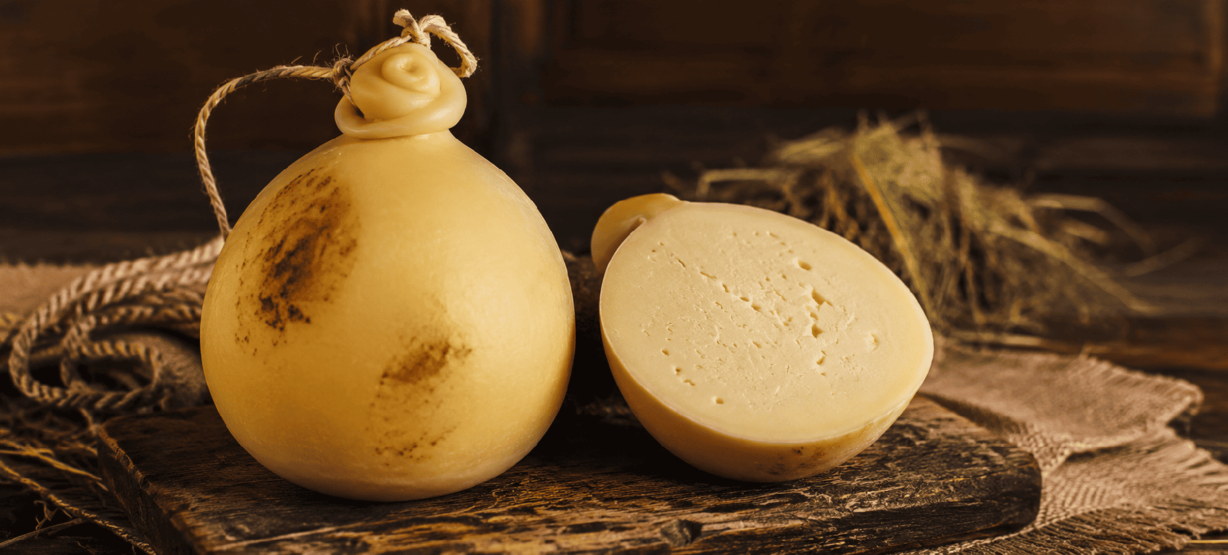 Formaggio Caciocavallo Podolico Lucano DOP intero e tagliato a metà su tagliere